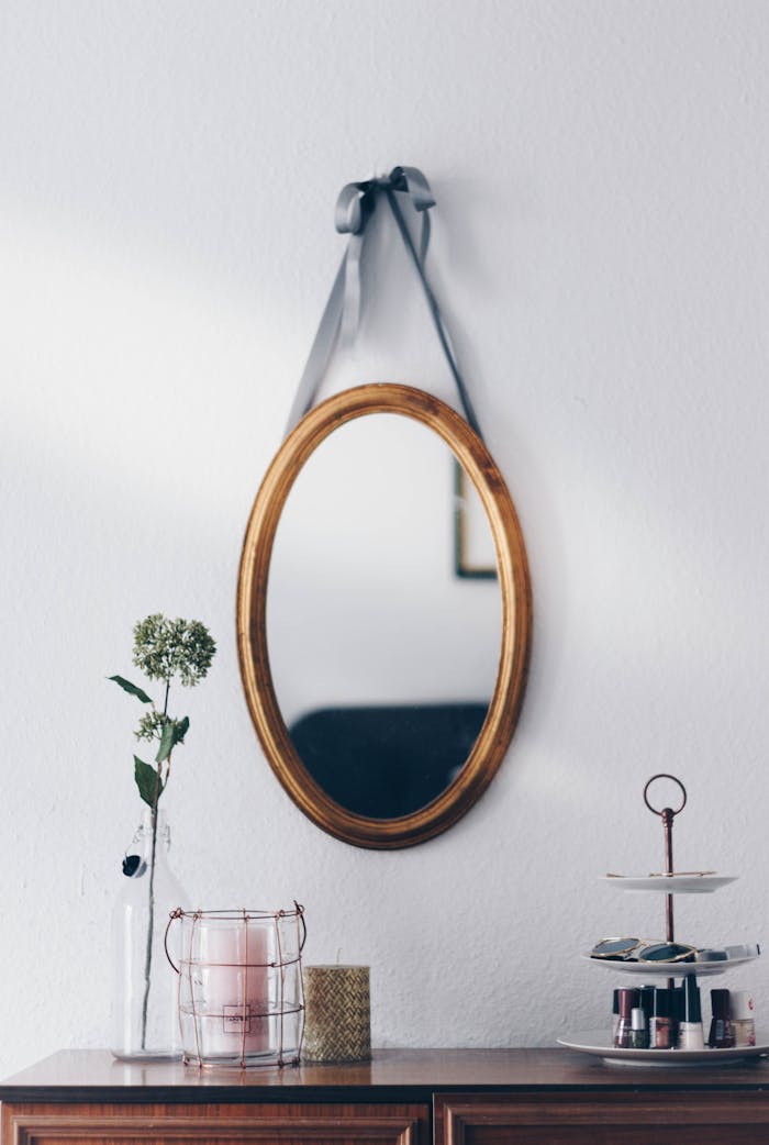 Mastering the First Impression: Your intriguing post title goes here A stylish interior setup featuring a hanging oval mirror with decorative elements on a wooden table.