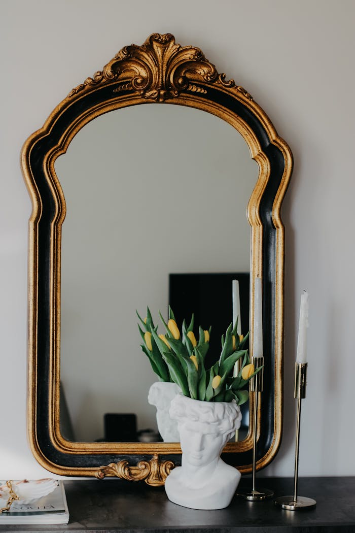 Crafting Captivating Headlines: Your awesome post title goes here A sophisticated interior featuring an ornate mirror, a bust vase with tulips, and elegant candles.